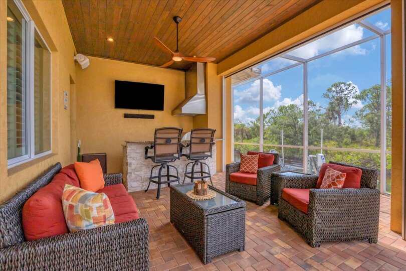 Large outdoor living space overlooking canal and nature preserve. Lanai features ample seating, outdoor kitchen, bar, 65-inch Smart TV, sparkling private pool & spa, and remote controlled privacy screens