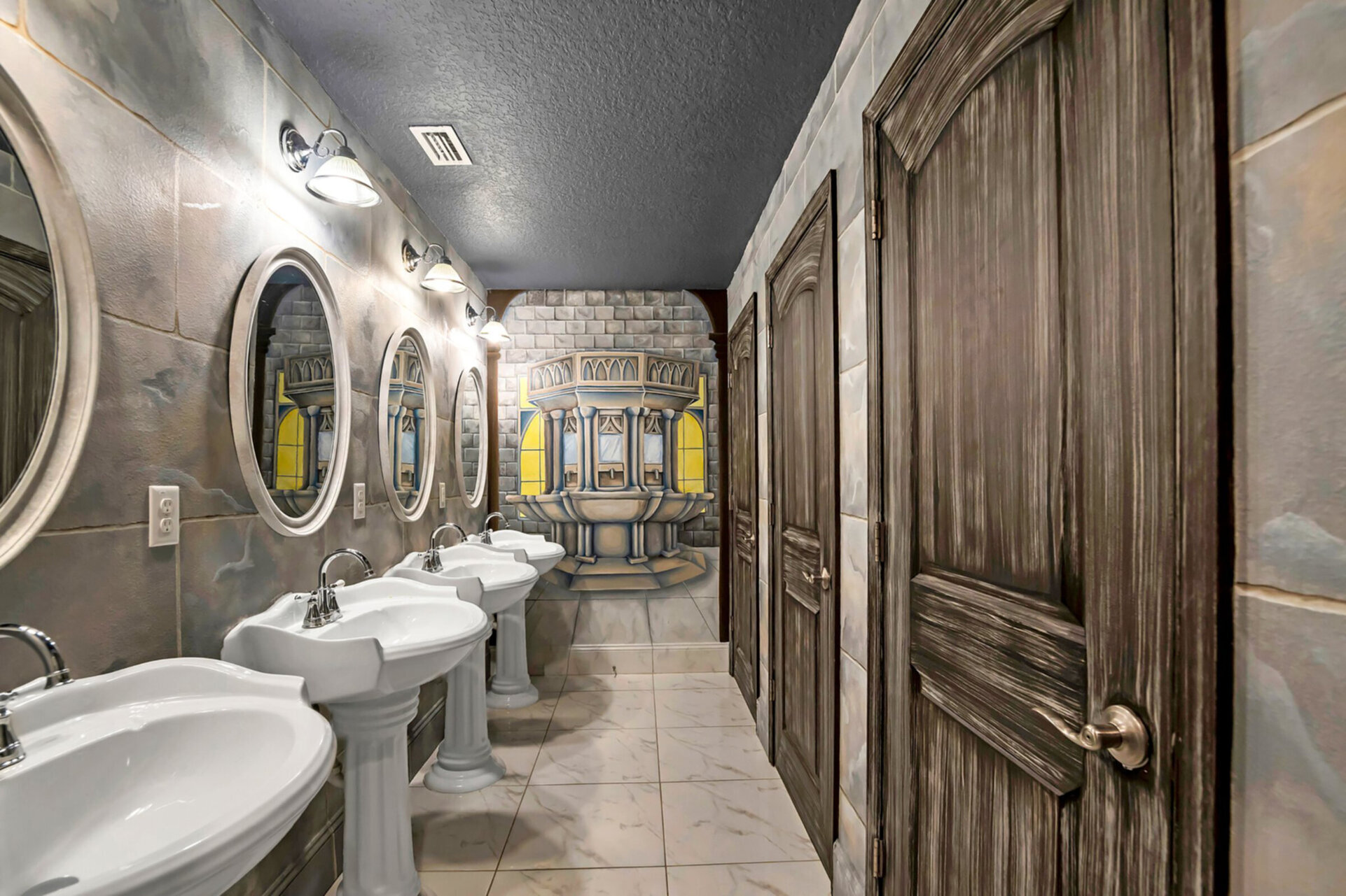 Step inside the lavatory which features 3 bathroom stalls, 3 walk in showers with glass doors and 4 separate vanities