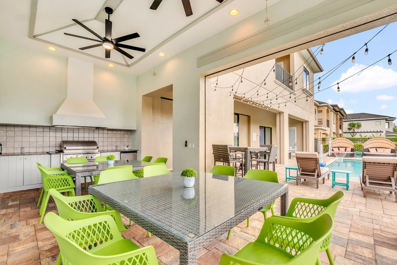 Dine al fresco in the summer kitchen with built-in BBQ, outside dining table, and TVs