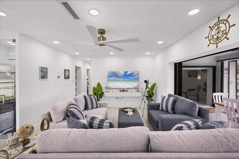 Living room overlooking the pool & canal. Living features ample & comfy seating, and 65-inch Smart TV