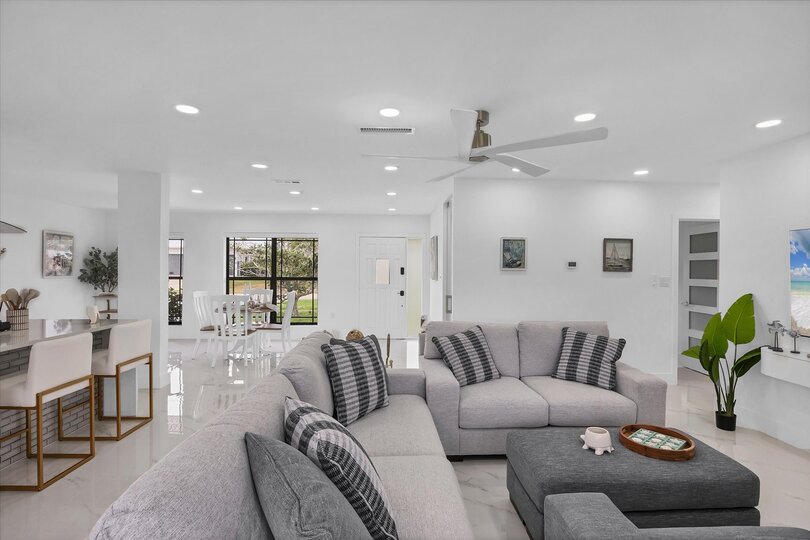 Living room overlooking the pool & canal. Living features ample & comfy seating, and 65-inch Smart TV