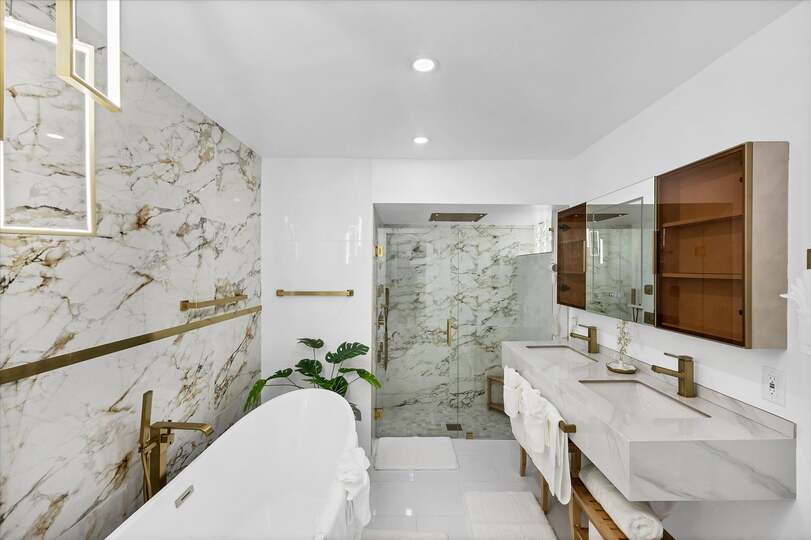 Double suite attached bathroom with walk-in shower, soaking tub, and double vanities