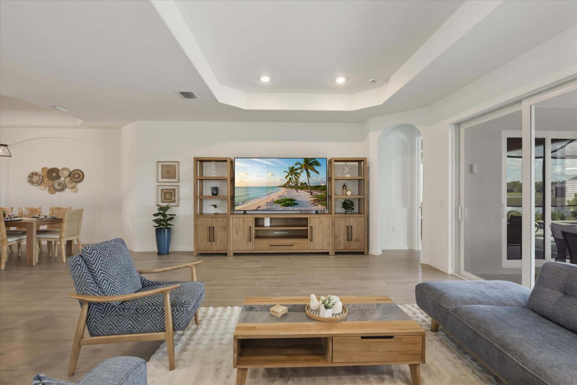 Living room overlooking the sparkling pool. Features ample seating and 85-inch Smart TV