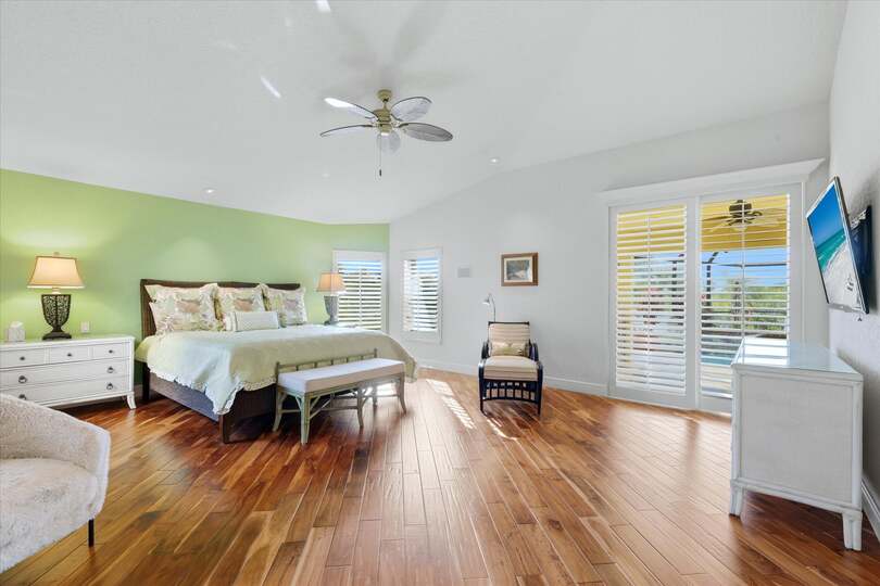 Huge primary bedroom with king bed, lanai acces, attached bathroom, desk & chair, and 55-inch Smart TV